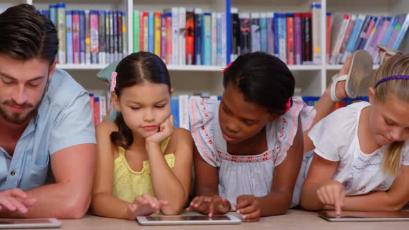 School kids and teacher using digital tablet in library