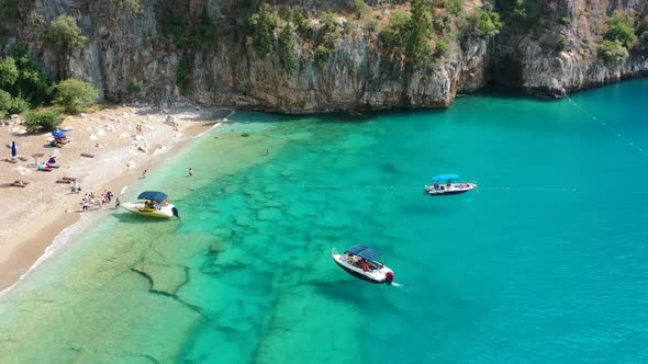 Aerial drone circling small tourist boats anchored in the transparent and crystal clear turquoise bl