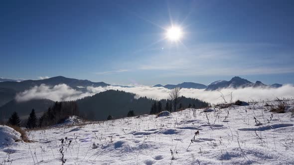 snow landscape with mountains and hills, low clouds moving over the hills, sunny day,