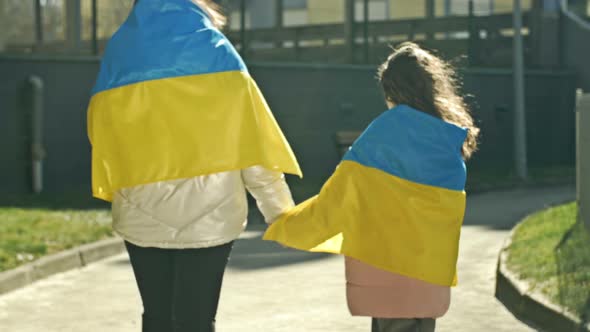 An Adult Woman Holds the Hand of a Little Girl