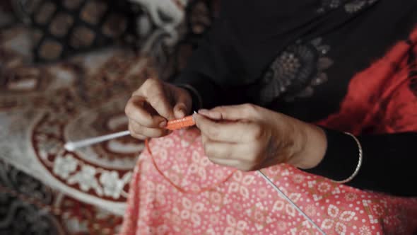 Footage from above of woman siting and knitting with red wool and needle crafts