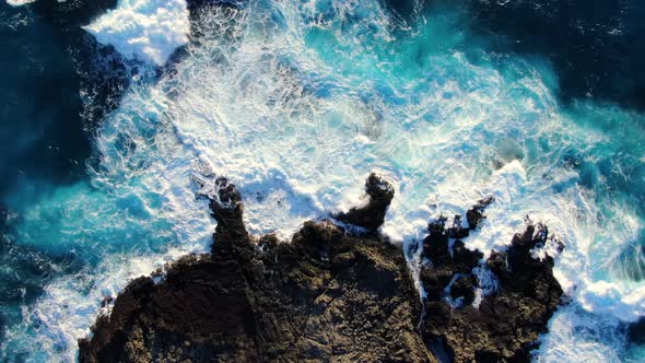 drone ascending above rocky shore as waves crash on the reef