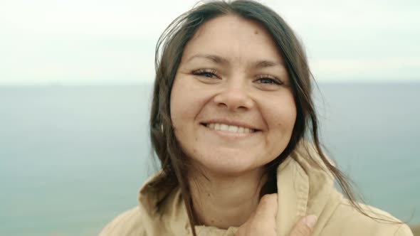 Portrait of a Brunette Girl Looking at the Camera on the Background of the Sea