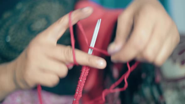 Woman starting knitting with the first row with red wool and needle crafts. Close up of knit work ti