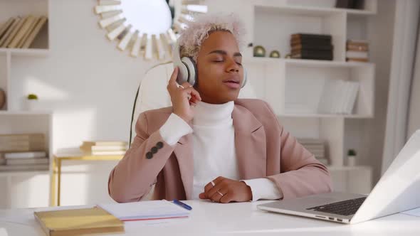 Young African American Woman Listening Music in Headphones at Office with Laptop