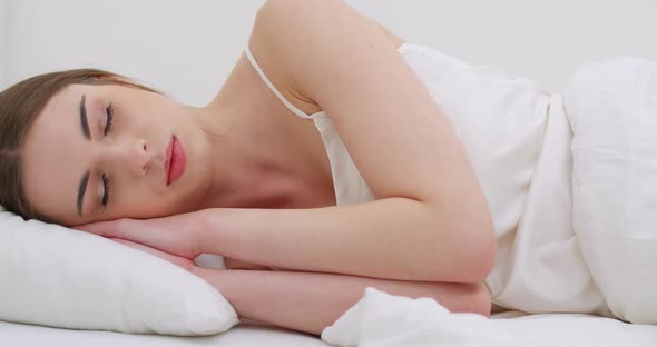 Young Female Sleeping in Bed, Waking Up in the Morning, Close-up of a Female Face, Woman Opens Her