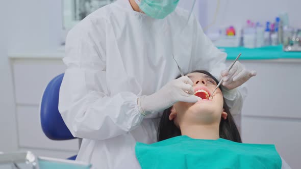 Asian young dentist wear mask, using medical instruments for oral care check up in dental clinic.
