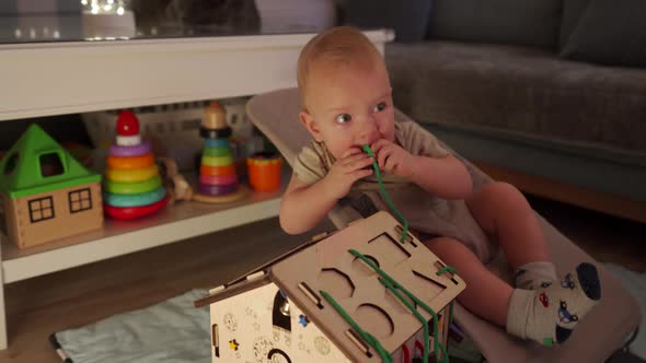 Adorable Baby Sitting in Infant Bouncer 10 Month Old Caucasian Kid Playing with Wooden Busy House