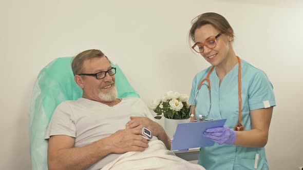 Doctor Talks To an Elderly Patient in a Hospital Ward