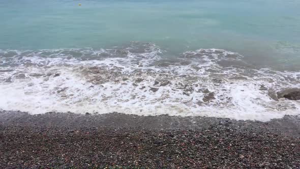 Waves Rushing on Shore at Sandy Beach Against City and Mountain