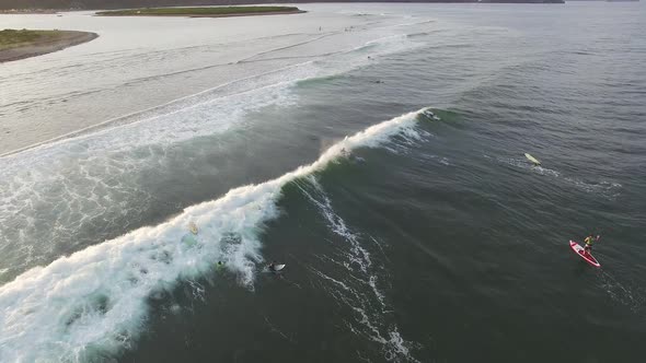 View From a Drone To a SUP Surfer Riding a Wave in the Sea at Sunset