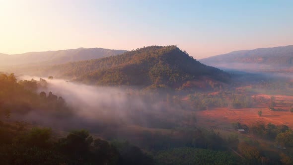 Aerial view from a drone over misty landscape on farmland. mountains in the background. 4K