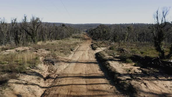 Drone aerial footage of telephone lines along a dirt road in regional Australia