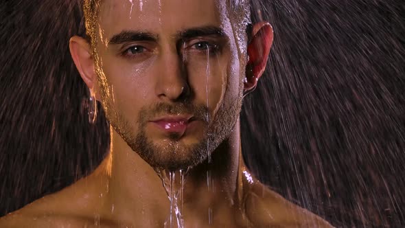 Portrait of a Sexy Young Man Under Shower Jets Who Looks Erotically Into the Camera, Water Flows