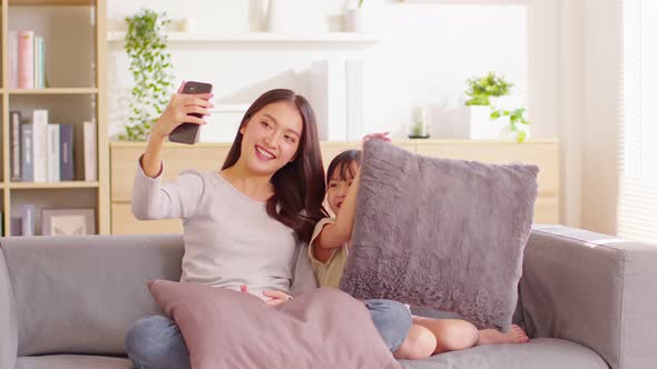 Asian young mother and her daughter have video call conference with family having fun together