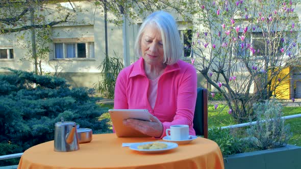 Woman in 70s Making a Video Call Outdoor with Tablet