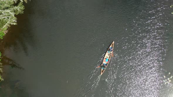 Beautiful close in drone shot of a canoe being paddled along a river