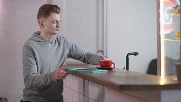 Unrecognizable Man Passing Coffee Cup for Student Surfing Internet on Tablet in Canteen