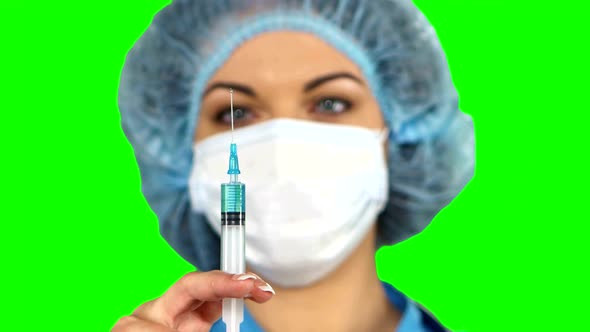 Young Nurse in Mask with Syringe on Green Screen