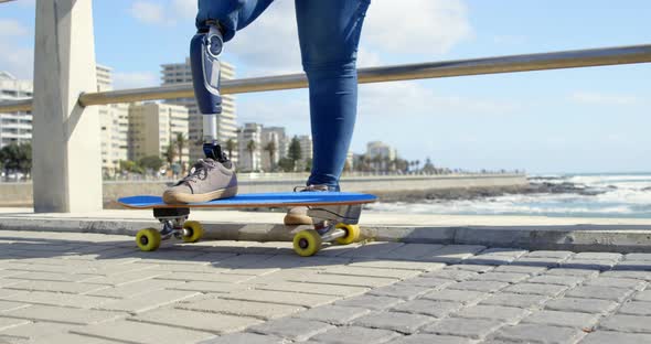 Low section of disabled woman standing with skateboard on promenade 4k