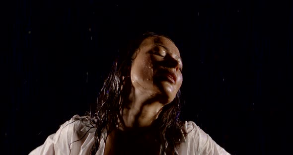 Close-up Portrait of a Beautiful Sexy Girl with Long Hair and a White Shirt. She Dances on a Black