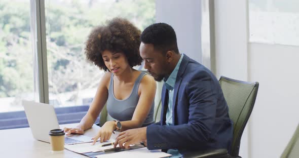 Video of focused diverse businessman and female designer working with laptop