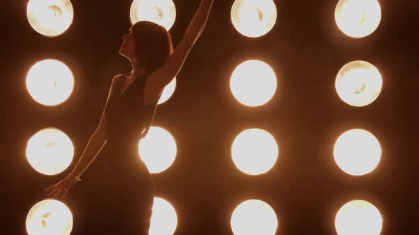Beautiful woman dancing in front of a wall of lights