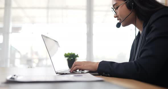 Happy female glasses wears headset video calling on laptop