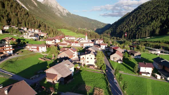 Aerial View of an Austrian Village in a Green Mountain Valley at Sunset Alps