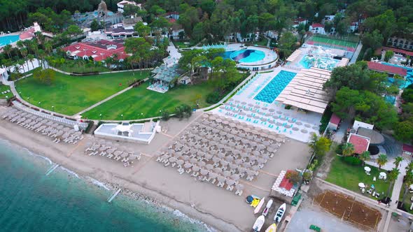 Flight Over the Beach with Umbrellas Towards the Pool in a Luxury Hotel