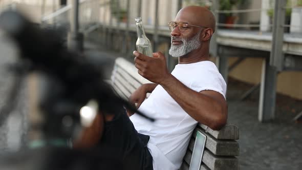 Man sitting on a bench enjoying his after-work beer