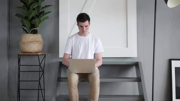 Excited Man Celebrating Win on Laptop While Sitting on Stairs