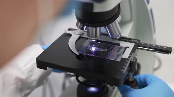 A Female Scientist Works in a Laboratory Behind a Microscope