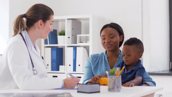 Happy Mother with Baby Son and Doctor at Clinic