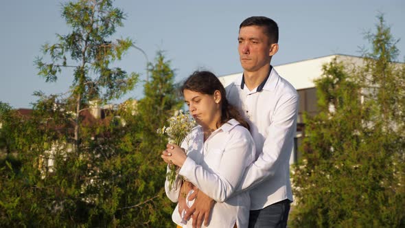 Young Disabled Woman Enjoys Smell of Bouquet and Kisses Man