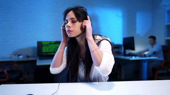 Serious Slim Beautiful Woman Putting on Headphones and Typing on Keyboard
