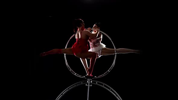 Two Air Acrobats Rotate in the Air While on a Metal Hoop. Black Background. Slow Motion