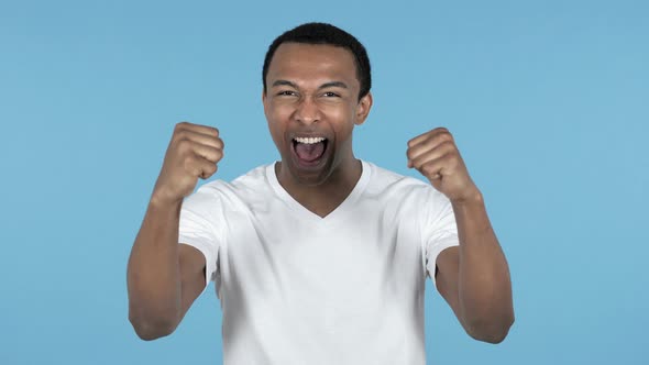 Young African Man Celebrating Success, Blue Background