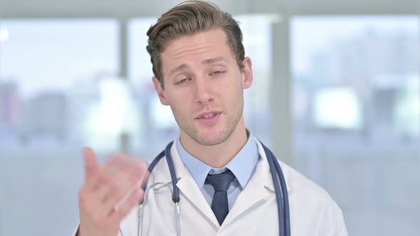 Portrait of Cheerful Young Male Doctor Doing Video Chat in Office 