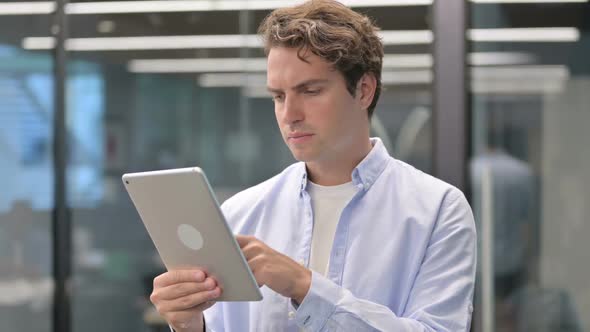 Portrait of Attractive Man Using Tablet in Office