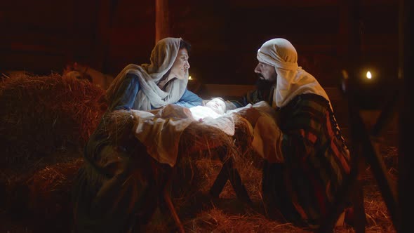 Mary and Joseph Caressing Baby Jesus in Illuminated Manger