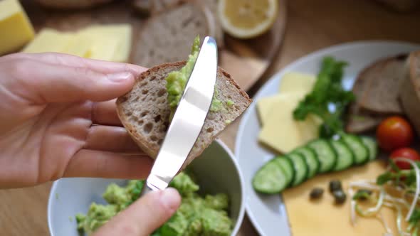 Top View of Spreading Mashed Avocado on Slice of Wholegrain Bread. Healthy Organic Vegan Breakfast