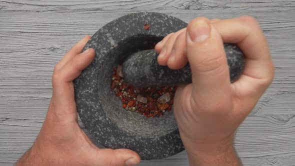 The Top View of a Pestle Grinding Spices Peppers and Sea Salt in a Grey Mortar