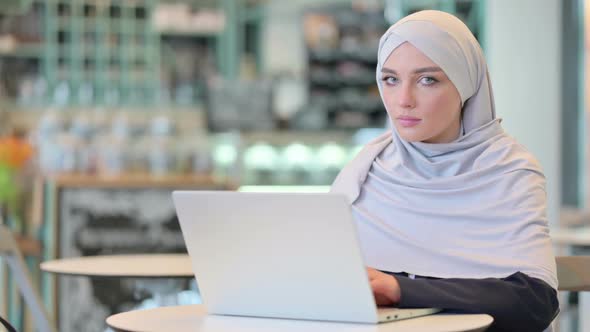 Cheerful Young Arab Woman with Laptop Smiling at Camera