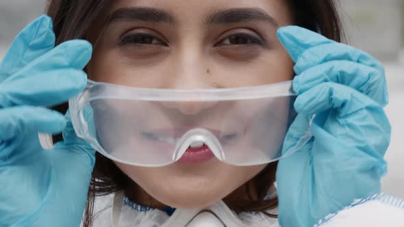 Cheerful Female Medical Worker Taking Off Protective Glasses Outdoors