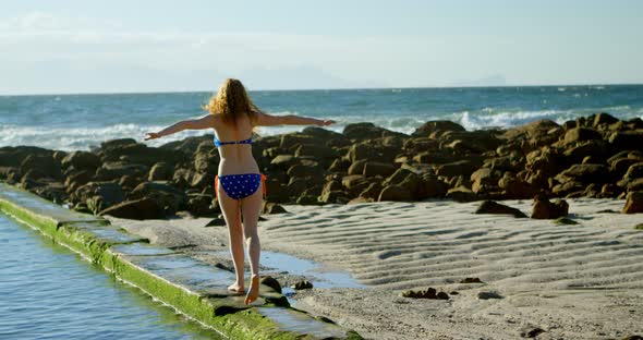 Woman walking with arms outstretched at beach 4k