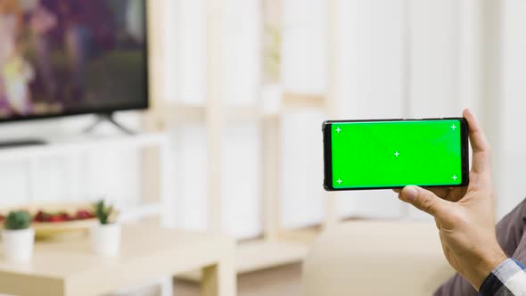 Holding a Green Screen Phone in Hand in Bright and Well Lit Living Space