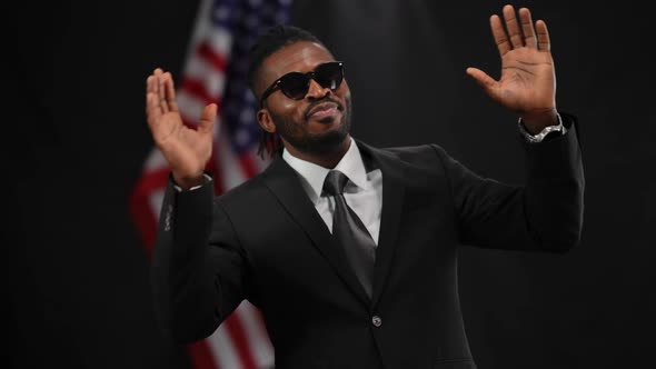 Portrait of Happy African American Man in Suit Putting on Sunglasses Dancing and Smiling As Dollars