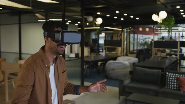 Mixed race businessman standing anfd using vr googles in a modern office