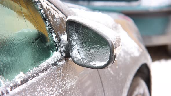 Close Up Of Right Side Mirror Of A Parked Car With Snow Defrosting